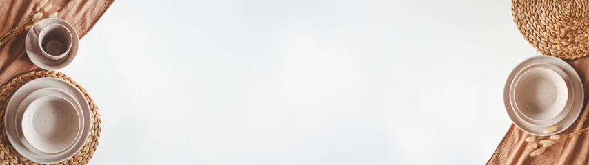 Minimalist table setting with plates, cup, and natural elements on a white background