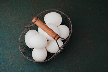 Closeup view of white chicken eggs in rustic wire basket concept for healthy cooking or natural food ingredient photography