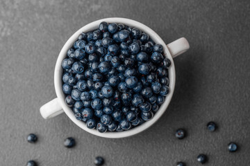 Blueberries with scattered berries on grey for healthy snack or food styling concept
