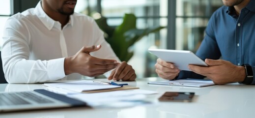 Business Meeting with Two Professionals Discussing Documents and Using a Tablet in a Modern Office Setting
