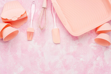Cupcake silicone molds and pink baking utensils on pink wall background