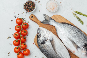 Close up of dorado fish tomatoes lemon and spices on cutting board