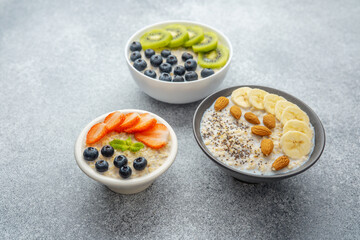 Oatmeal porridge with strawberries blueberries and mint in white bowl