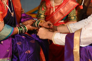 Indian Groom Tie a Turmeric Thread on hand of bride. Close Up Hands of bride and Groom in hindu wedding. Marathi Wedding Ceremony. Maharashtra Culture. Hindu wedding rituals and ceremony. Yellow knot