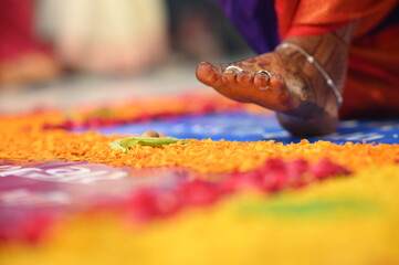 Leg of bride touch the stone in indian wedding ceremony. seven steps wedding ceremony. flowers petals and leaf. colorful steps. close up