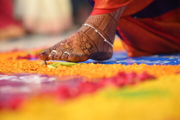 Feet of bride touch the stone in indian wedding ceremony. seven steps wedding ceremony. flowers petals and leaf. colorful steps