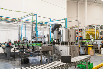 Beer bottles conveying on an automated production line in a modern brewery processing plant, filling liquid drink