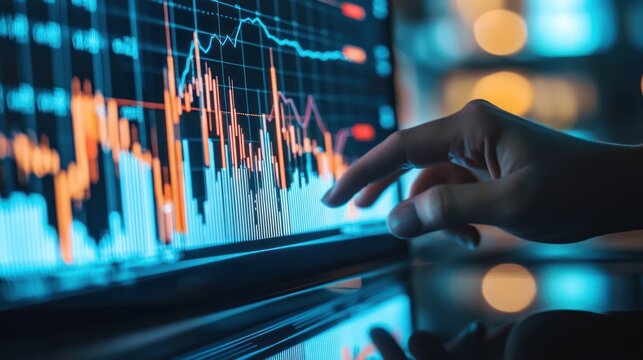 Close-up of a hand interacting with a glowing digital screen displaying financial market data, charts, and graphs in a low-light professional setting, symbolizing business analysis and investment.