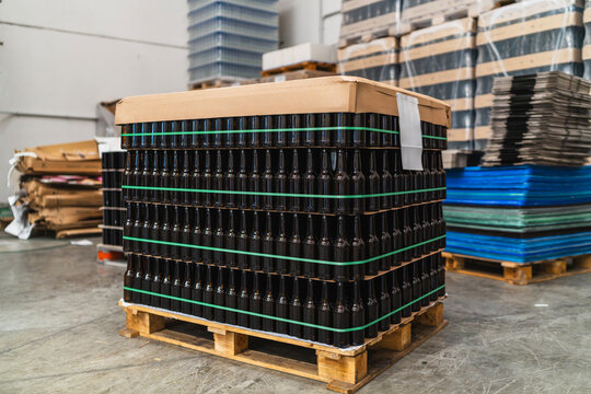 Pallet of dark glass beer bottles ready for shipping, representing the beverage production and distribution industry