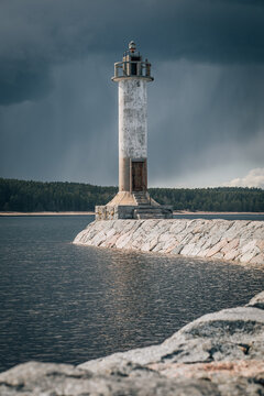 Lighthouse standing against storm clouds on rocky breakwater