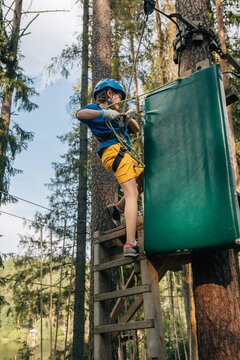 Boy attaching safety rope on forest high ropes platform, gloves