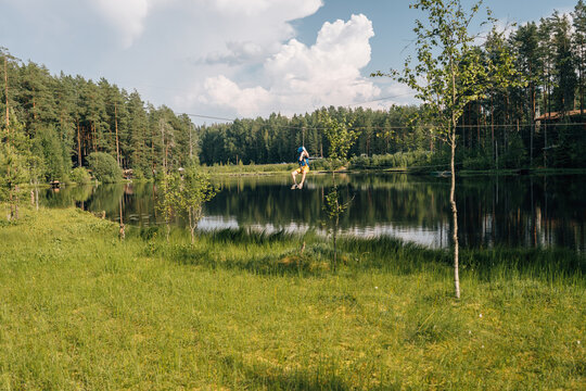Boy riding zipline over forest lake, summer adventure