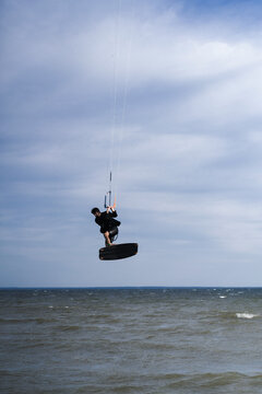 Kitesurfer performing extreme trick high above the wavy summer lake