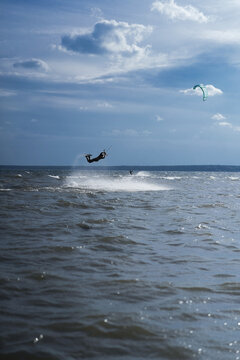Kitesurfer performing extreme jump with massive spray