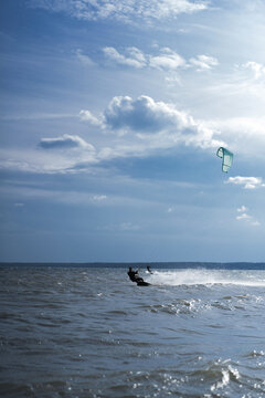 Kitesurfer generating large water spray while riding fast
