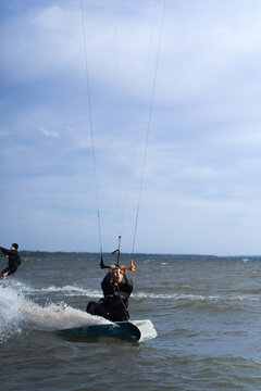Kitesurfer in wetsuit gliding across choppy water on a sunny day