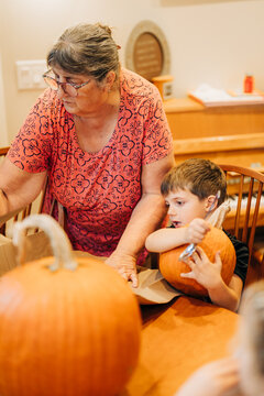 Grandmother and grandson carving pumpkins celebrating halloween