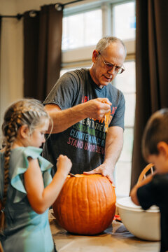 Grandfather and children carving halloween pumpkin together