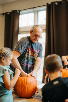 Grandfather and children carving pumpkins for halloween tradition