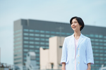 Fototapeta premium 青空と白衣を着た30代女性医師