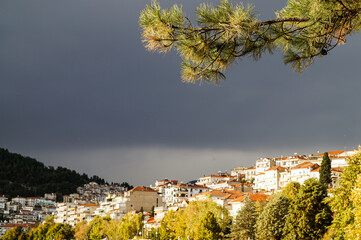 Kastoria, Greece. Scenic waterfront view of Kastoria town during autumn, buildings reflected in the lake water under dramatic clouds