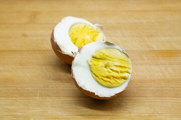 a boiled egg in its shell, cut in half, showing the texture of the white and yolk against the...