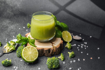 Green juice with broccoli, lime, basil, and salt on dark background