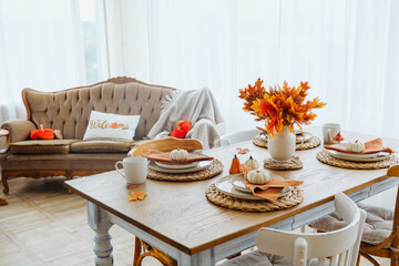 Cozy dining table set for autumn with pumpkins and oak leaf foliage