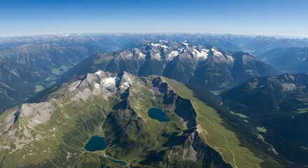 Aerial shot shows a vast mountain range with lakes, meadows, and peaks under a clear blue sky