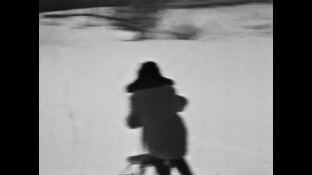 Happy child boy sledding down slope by kick sled in snowy forest in winter. Fun retro holidays. Joyful activity in nature cold. Nostalgic childhood joy. Vintage film. Old archive. Archival retro 1960s