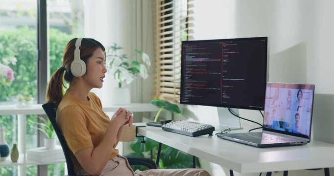 Young Asia female programmer meeting video conference discuss work prompt AI bot IT app program nomad, video game, terminal with coding, user interface, data center on desktop computer at home office.