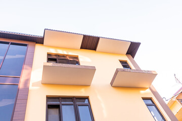 A view from below of a chic city building of a residential or hotel type. White beautiful balconies, bay window. light architectural solution.