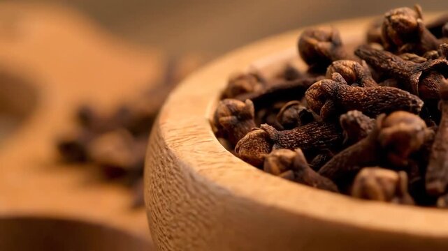 Aromatic dried clove spices in a wooden bowl close up.