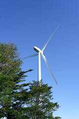 A white wind turbine stands powerfully under a clear blue sky in a vertical composition. This hopeful design is perfect for themes like environmental issues, new energy, and challenges for the future.