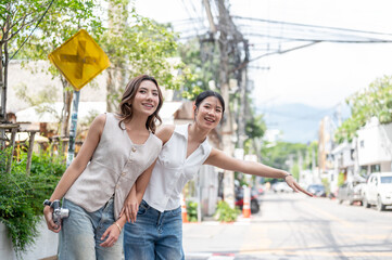 Naklejka premium Pretty asian woman holding camera and friend calling taxi while standing on sidewalk by street road.