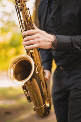 Obraz premium A man plays the saxophone in a park in autumn among falling leaves and yellow foliage. no face closeup