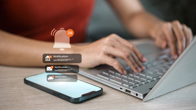 Mobile push notifications alert while woman typing on laptop, smartphone bell message concept
