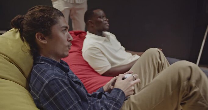 Diverse colleagues enjoy a break playing video games in a modern office environment. Teamwork and relaxation in the workplace.