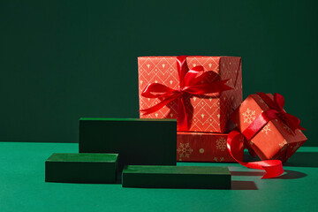 Minimal green background with red gifts and ribbon. Stylish, warm-toned layout for Christmas mockups or invitations. Noel concept, Christmas podium
