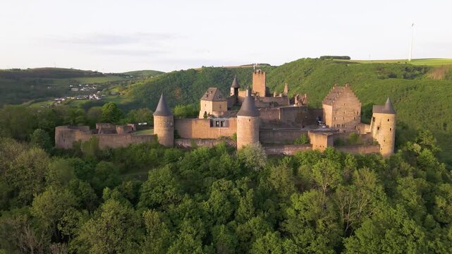 bourscheid castle ch&acirc;teau de green cover hills farms visitor vehicles parked compound windmill behind add detail to left right circles drone luxembourg circling 