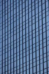 Fototapeta premium A section of a modern building with many rectangular glass windows reflecting the clear