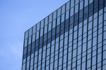 A section of a modern building with many rectangular glass windows reflecting the clear