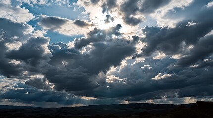 Obraz premium Dramatic cloudscape with sunlight piercing through, casting a serene glow over the distant horizon.