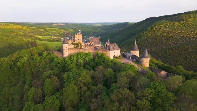 bourscheid castle ch&acirc;teau de show green cover hills farms river valley homes sunny day bird&rsquo;s eye perspective enrich pull circling drone back luxembourg 