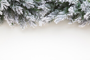 Green artificial fir branches covered with hoarfrost and white snow on light gray table background....
