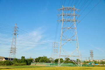 秋の田んぼと青空にそびえる鉄塔