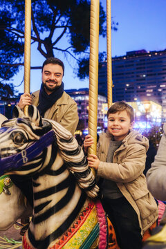 Father and son enjoying carousel ride at Plaza de Col�n in Madrid at night