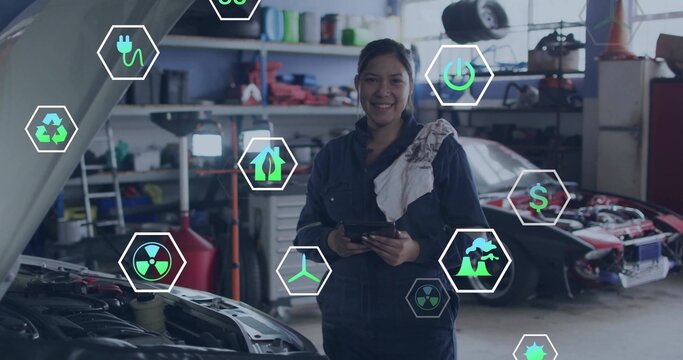 Female mechanic holding tablet, examining engine under hood in repair bay, with hex energy icons