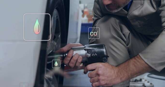 Kneeling mechanic tightening wheel with impact wrench in shop, CO? drop overlay, copy space