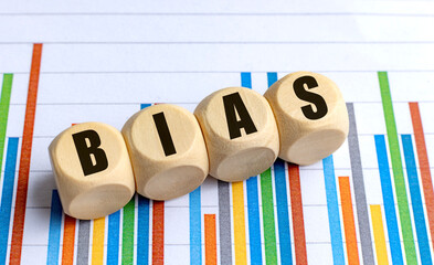 Bias word on round wooden blocks placed on colorful statistical bar chart background